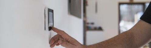 Man at home adjusting wall thermostat
