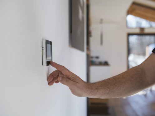 Man at home adjusting wall thermostat