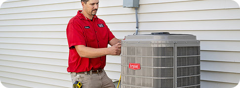 technician in red shirt working on air conditioning unit