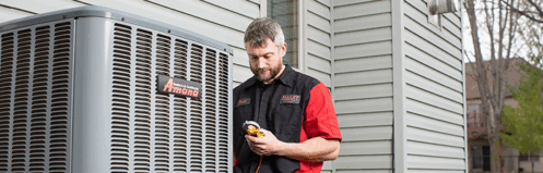 an hvac technician works on an air conditioning unit on the side of a home
