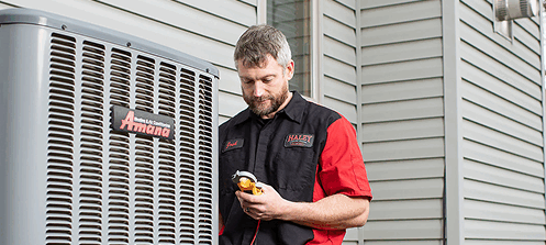 an hvac technician works on an air conditioning unit on the side of a home
