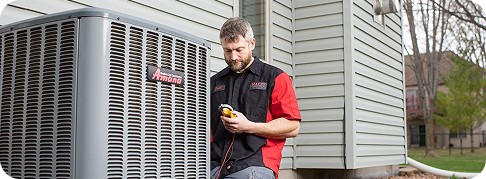 an hvac technician works on an air conditioning unit on the side of a home