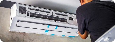 a white ductless unit on a wall as a technician installs it