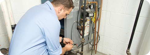 technician in blue shirt working on furnace unit