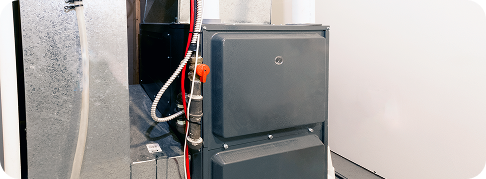 close up of dark grey furnace unit connected to wires and hoses