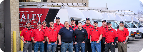 Haley employees smiling for a group photo in front of work vans
