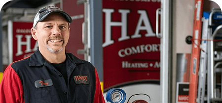 Haley Comfort Systems technician smiling in front of a company service truck